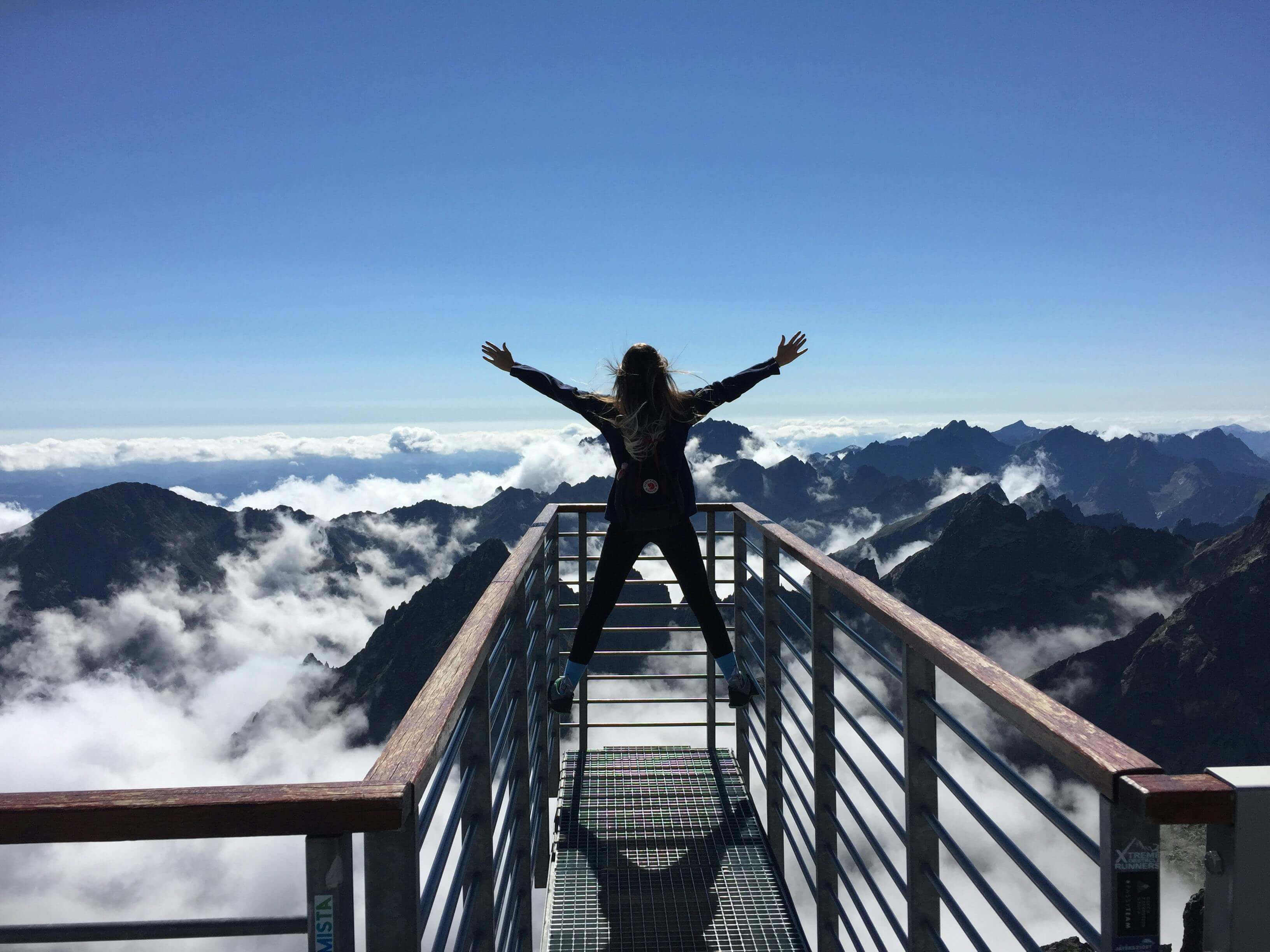 Girl with open arms in front of the mountains